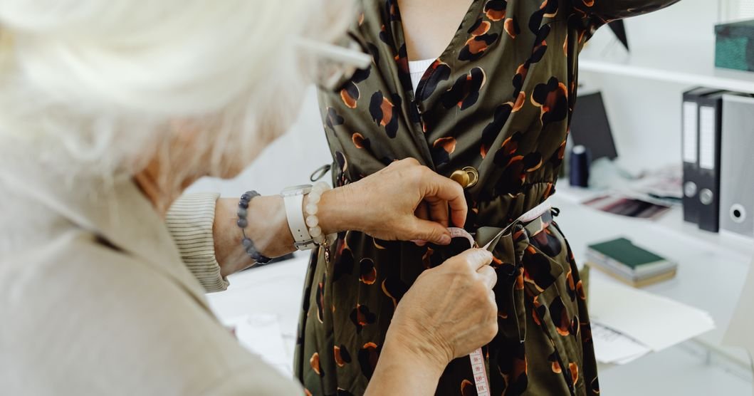Tailors hand-stitching black abayas with gold trim in a traditional Gulf souq workshop