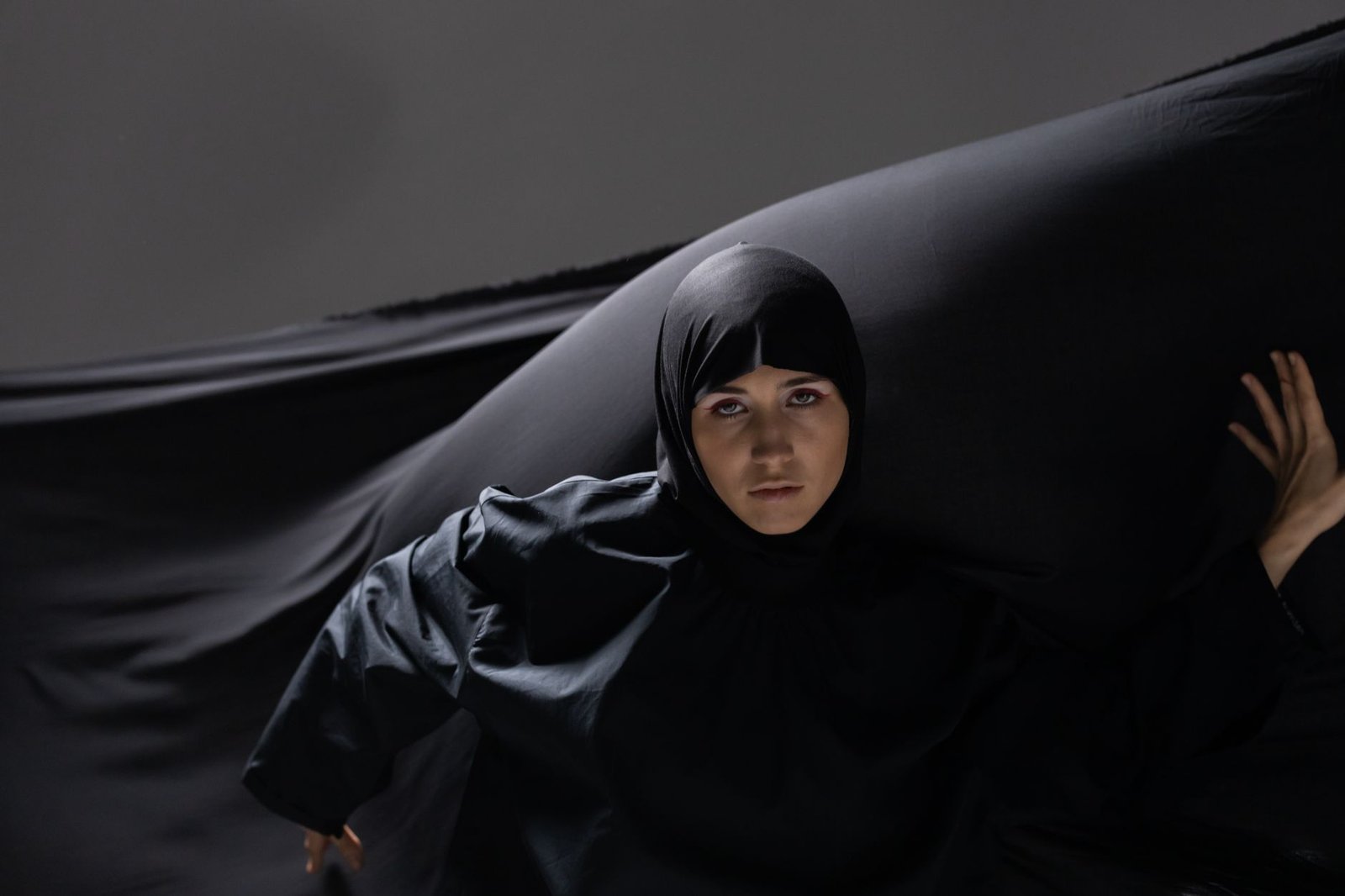 Woman wearing a black open-front abaya layered over an everyday outfit