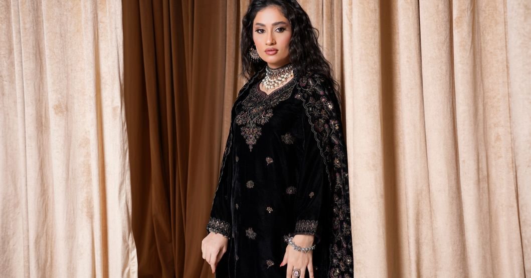 Woman in a floor-length black velvet evening abaya with soft light catching the pile