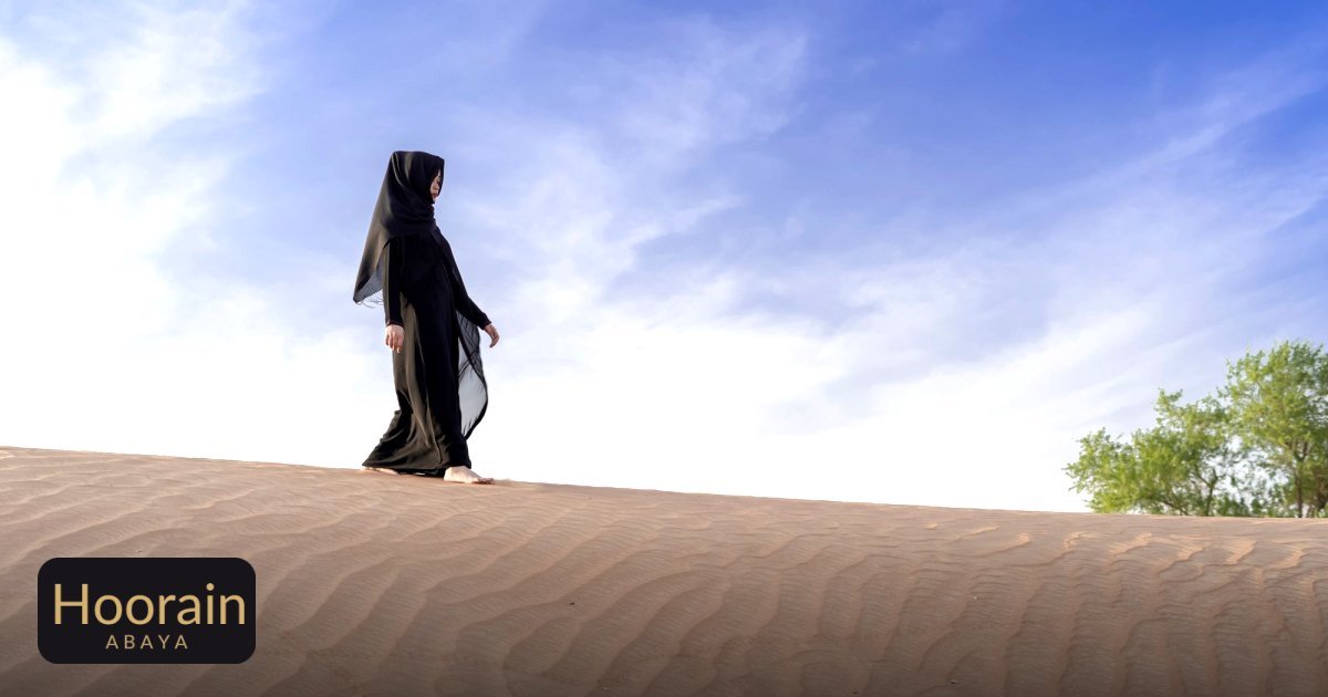 How to Wash an Abaya: Care Guide for Every Fabric - a woman in traditional abaya walking on a desert sand dune under a clear