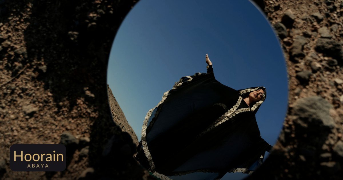 Ramadan Abaya Ideas: Light Open Abayas for Iftar - a woman in a traditional abaya is reflected in a mirror placed on rocky
