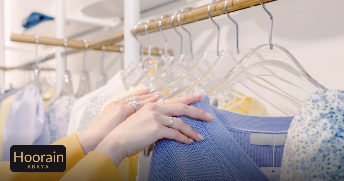 Travel Abaya Guide: Wrinkle‑Resistant Fabrics & Packing Tips - hands selecting colorful sweaters on a clothing rack inside