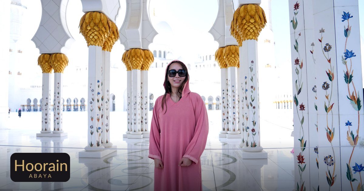 Travel Abayas for Long Flights: Wrinkle-Free Elegance - a woman in a pink abaya stands in the , surrounded by ornate columns
